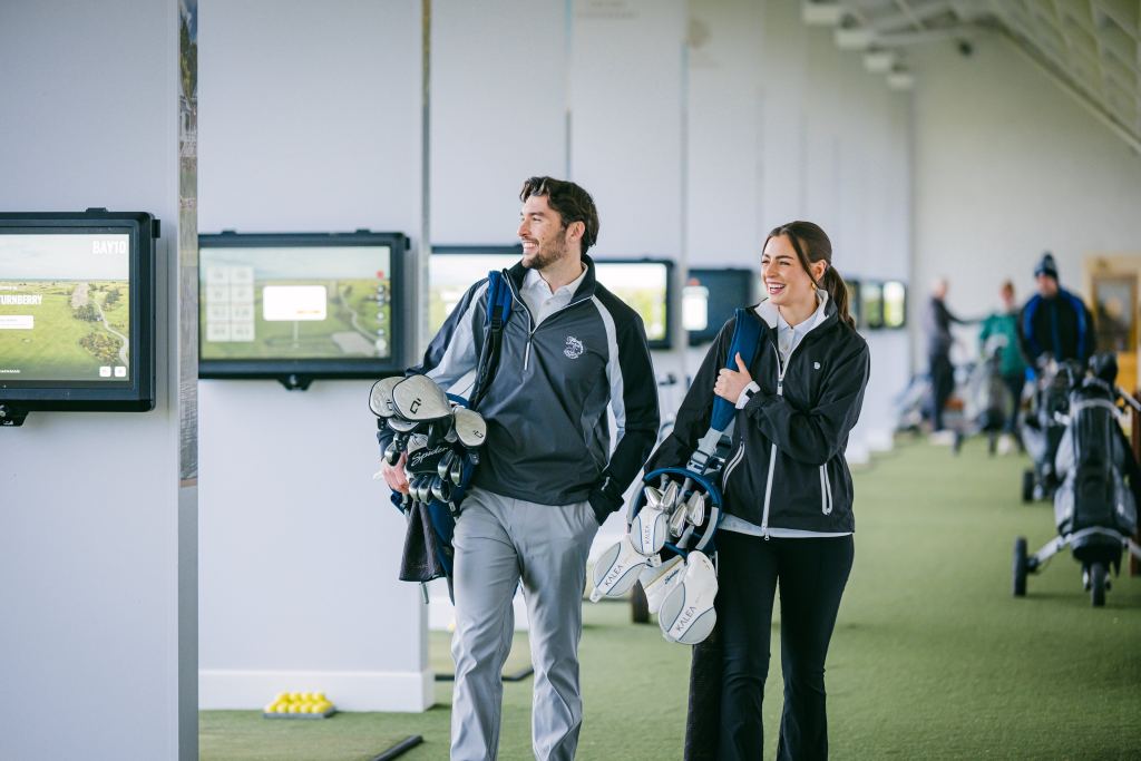 Two golfers arriving at the range with their clubs