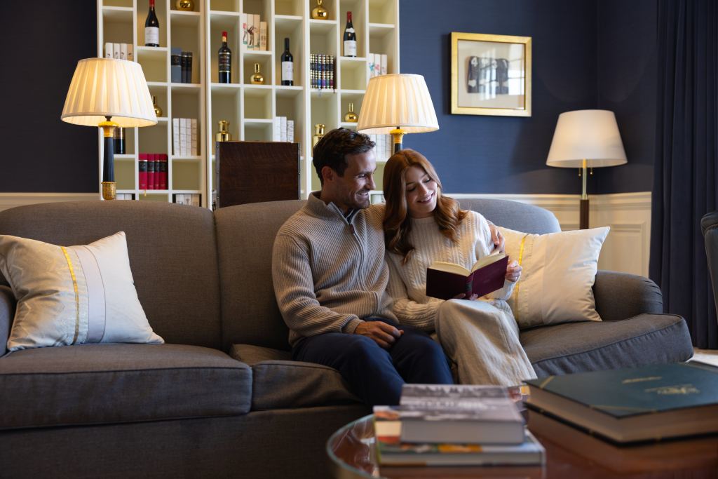 A couple relaxing in a library with whisky on the shelves