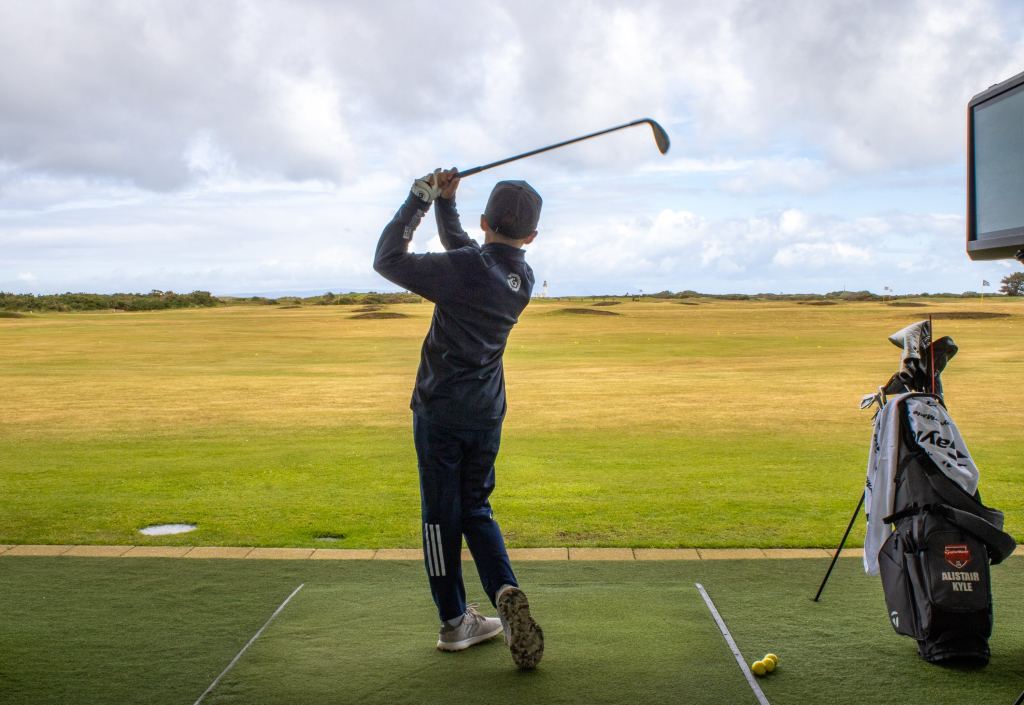 A golfer on the range with his bag beside him